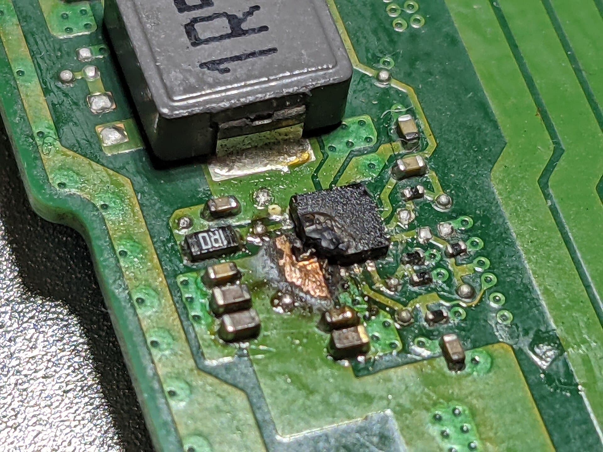 A burnt power regulator on a laptop motherboard, seen under a microscope