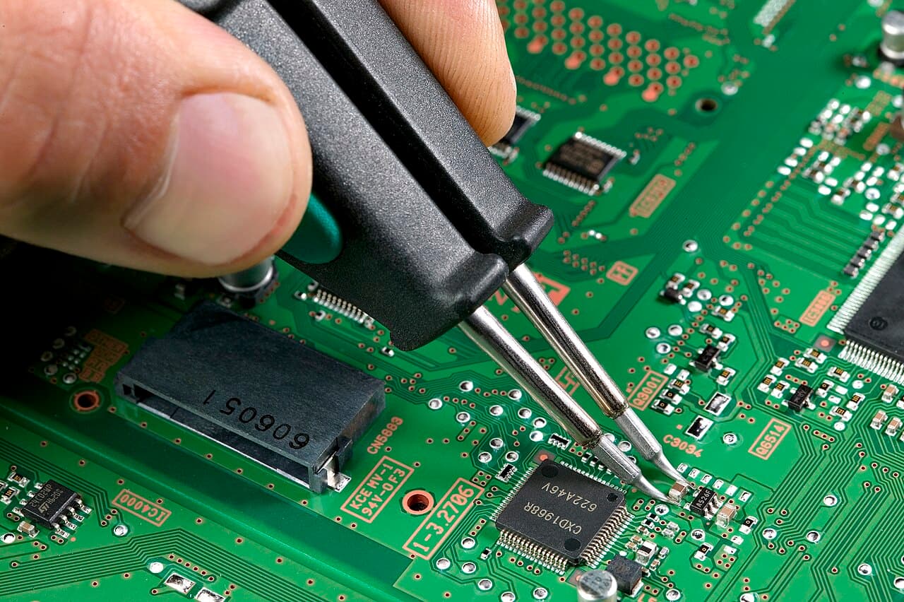 Tweezers placing a tiny component on a circuit board